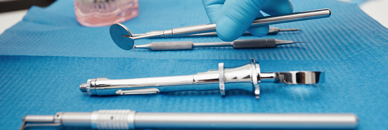 Set of metal medical equipment tools for teeth dental care. Doctor takes medical instruments. Hand of dentist reaching for dental instruments in a cabinet.